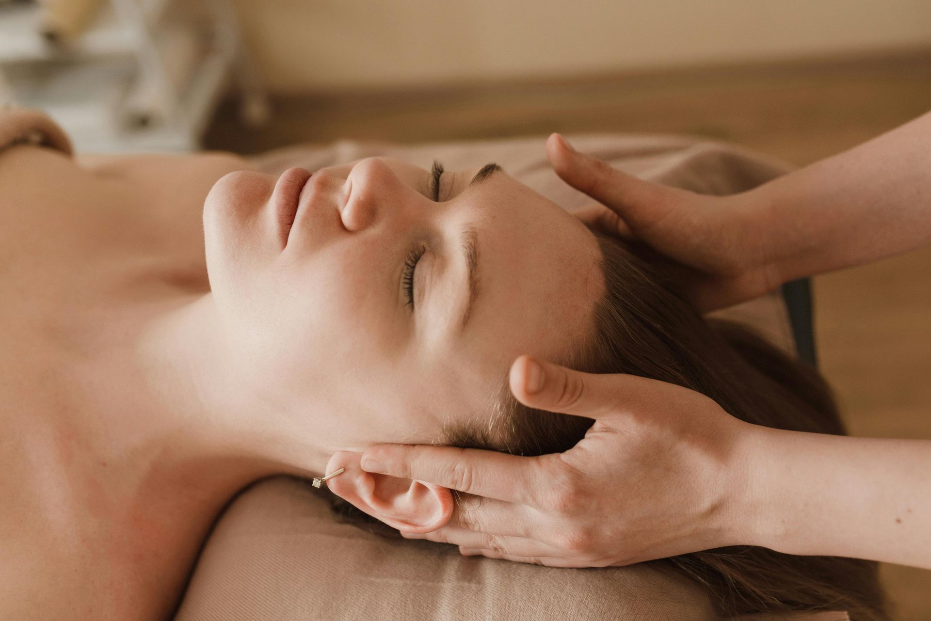 Een persoon die een gezichtsmassage krijgt met de handen op het voorhoofd in een spa.