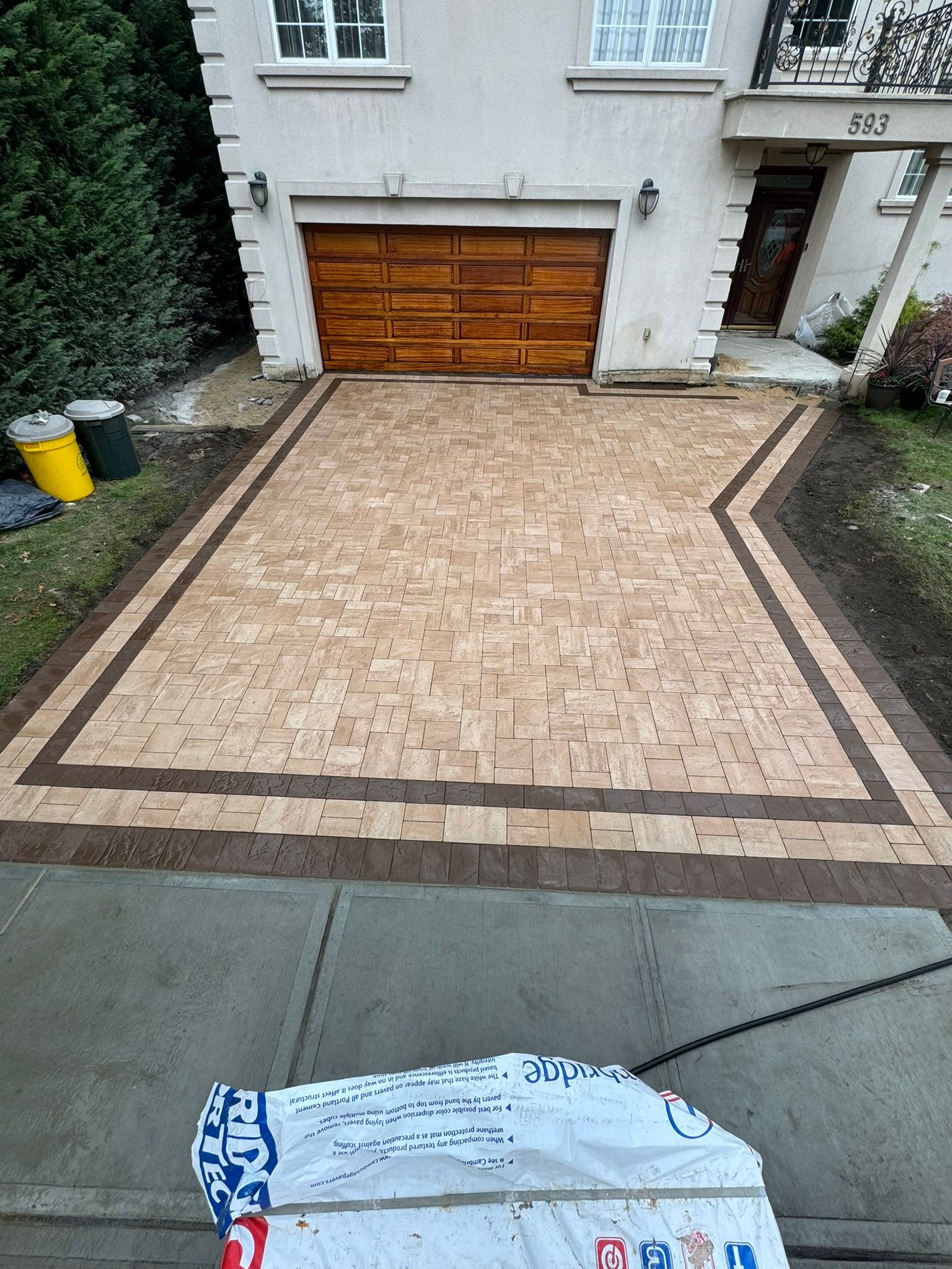 A brick driveway in front of a house with a wooden garage door.