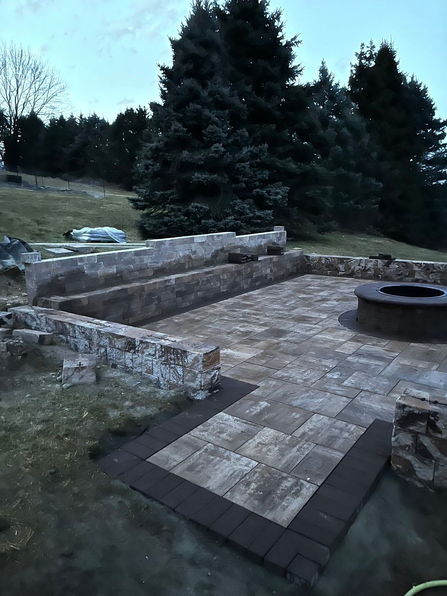 A patio with a fire pit and trees in the background