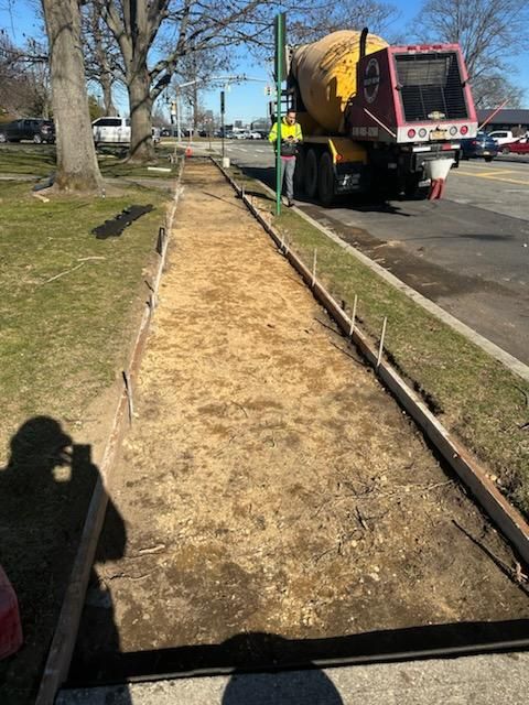 A concrete mixer truck is pouring concrete on a sidewalk.