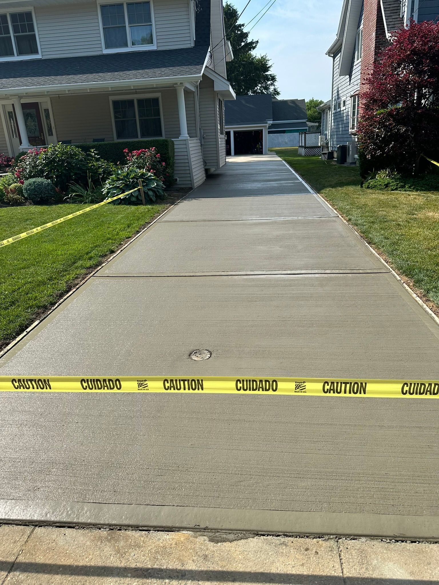 A concrete driveway leading to a house with a yellow caution tape.