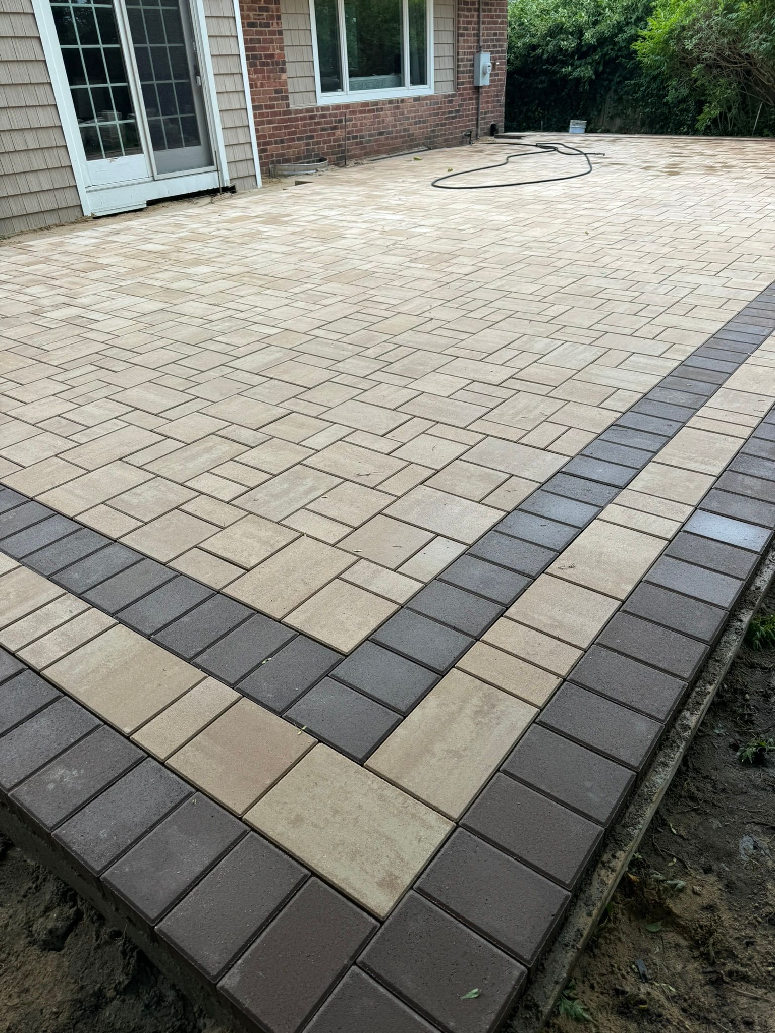 A brick patio is being built in front of a house.