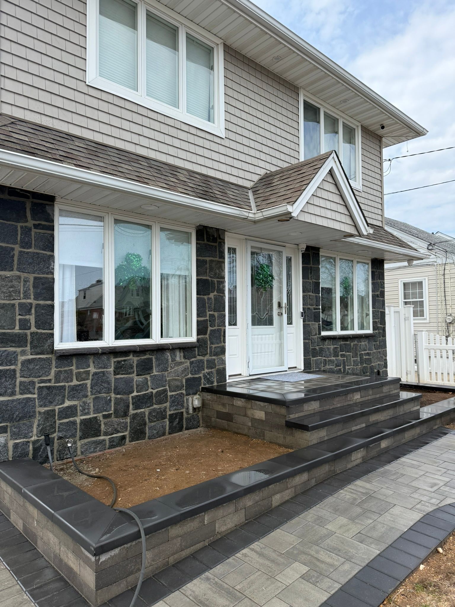 A large house with a stone facade and a brick walkway leading to the front door.
