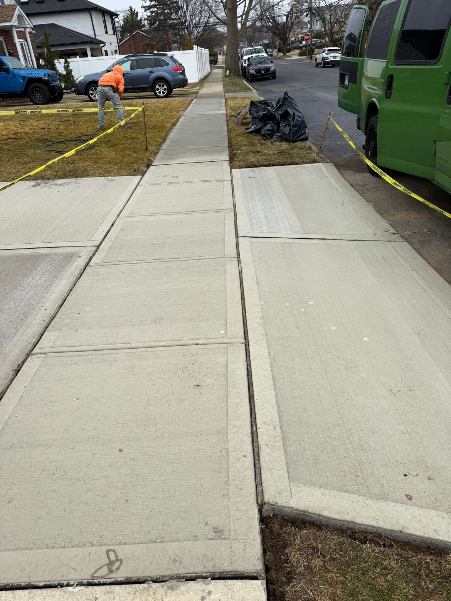 A man is working on a sidewalk next to a green van.
