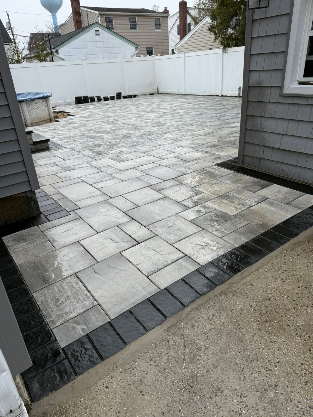 A patio with a black border is being built in front of a house.