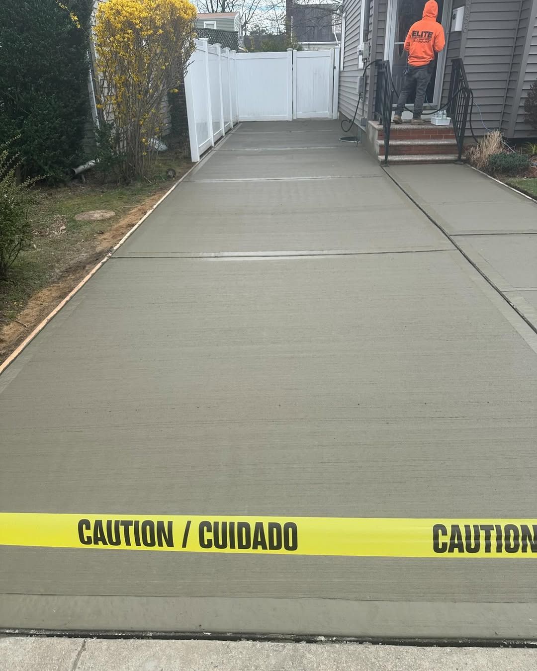 A concrete driveway with a yellow caution tape on it.