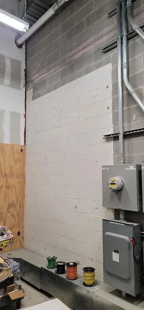 Interior construction site with drywall, electrical boxes, and paint cans.
