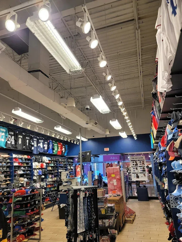 Interior of a sports apparel store with merchandise displayed on shelves and racks under bright lighting.