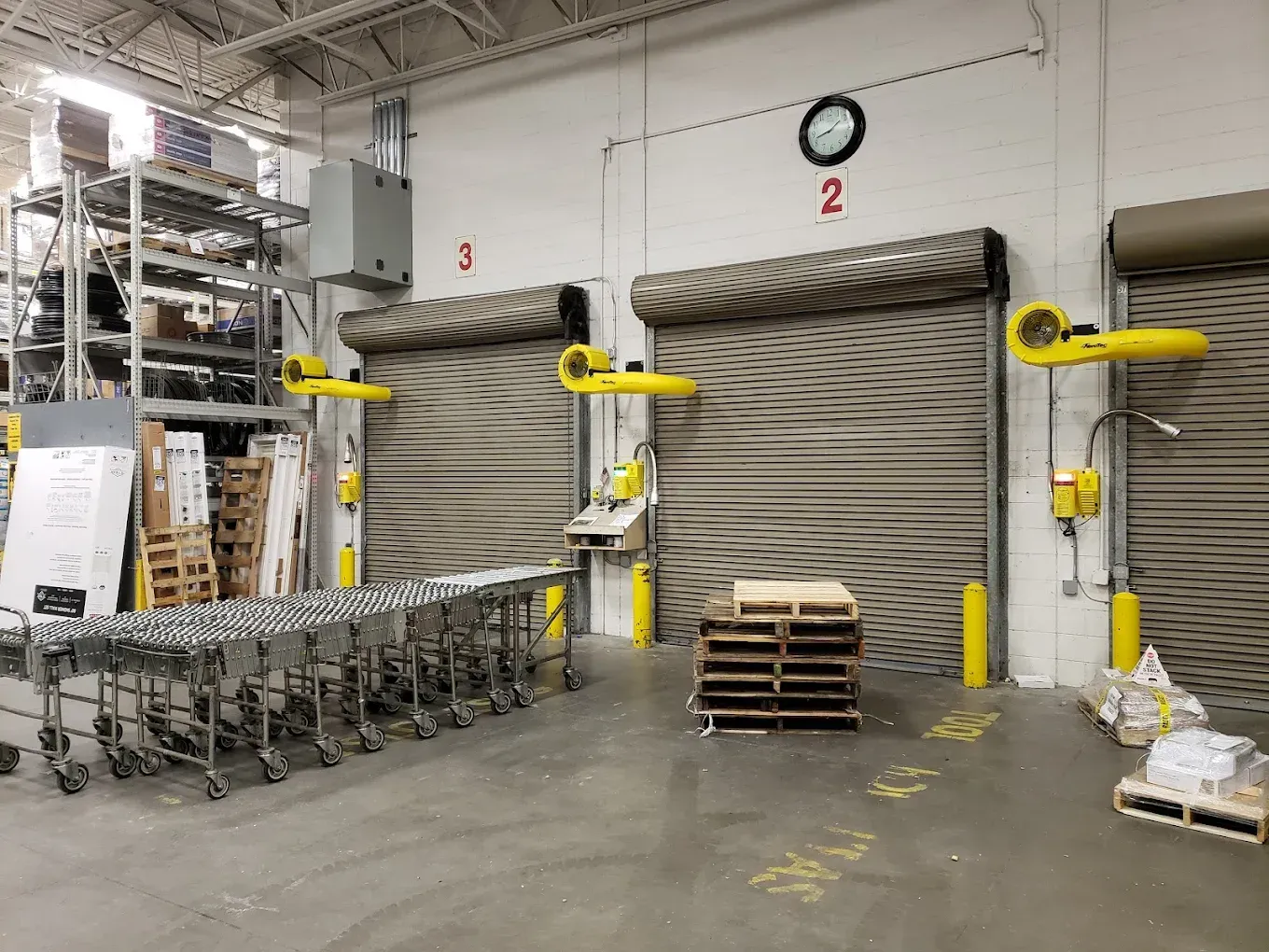Loading dock area with three overhead doors numbered 2 and 3. Pallets, conveyor, and equipment visible.