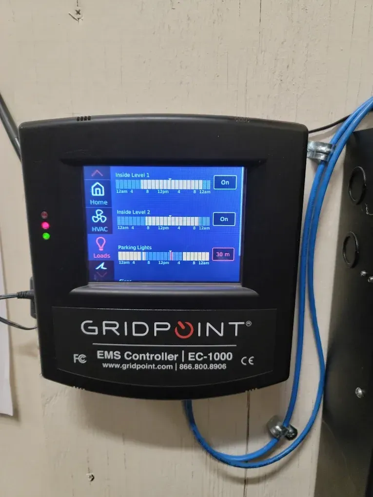 Black Gridpoint EMS Controller EC-1000 with a screen displaying data, mounted on a wall.