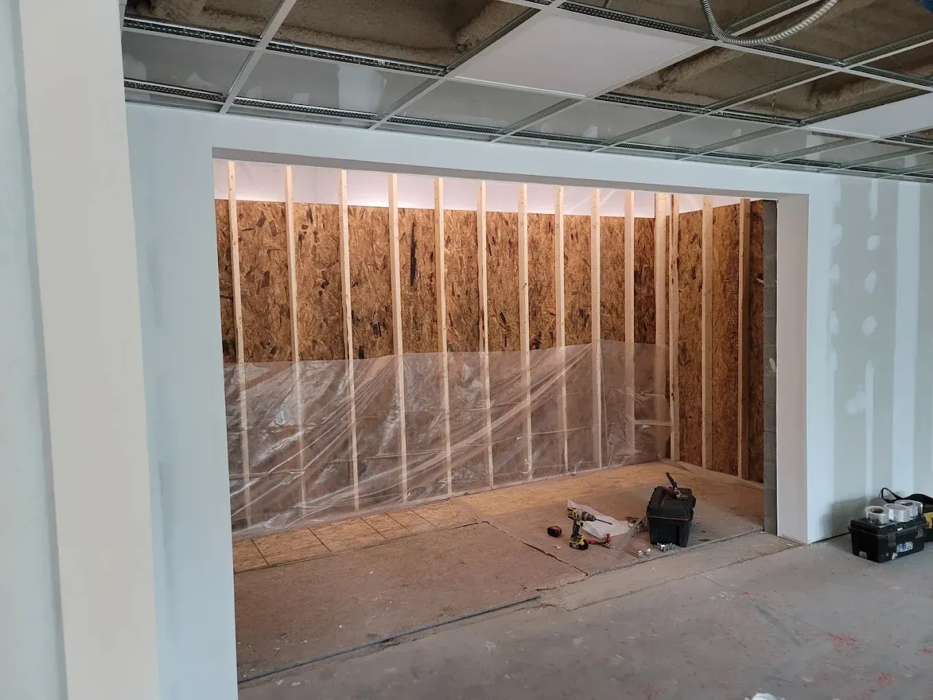 Interior view of a room under construction with exposed wooden studs, insulation, and partially finished walls.