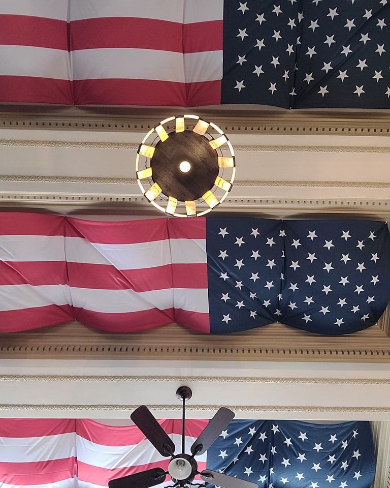American flags and stars and stripes decorations on ceiling with a light fixture and ceiling fan.