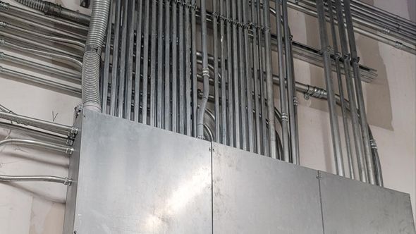 Metal electrical conduit pipes are installed on a wall.