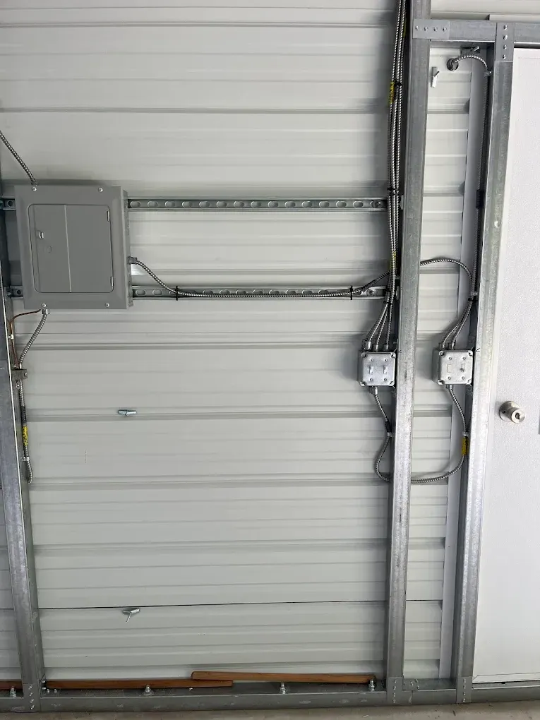 Electrical panel, conduit, and outlets mounted on a metal-walled structure.