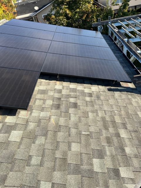 Solar panels installed on a residential roof. Panels are black, roof is grey asphalt shingles.