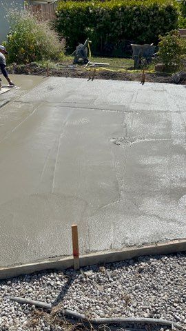 Freshly poured concrete slab being smoothed, outdoors.