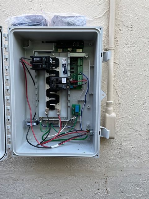 Open gray electrical box on a wall, containing wires, circuits, and a circuit board.