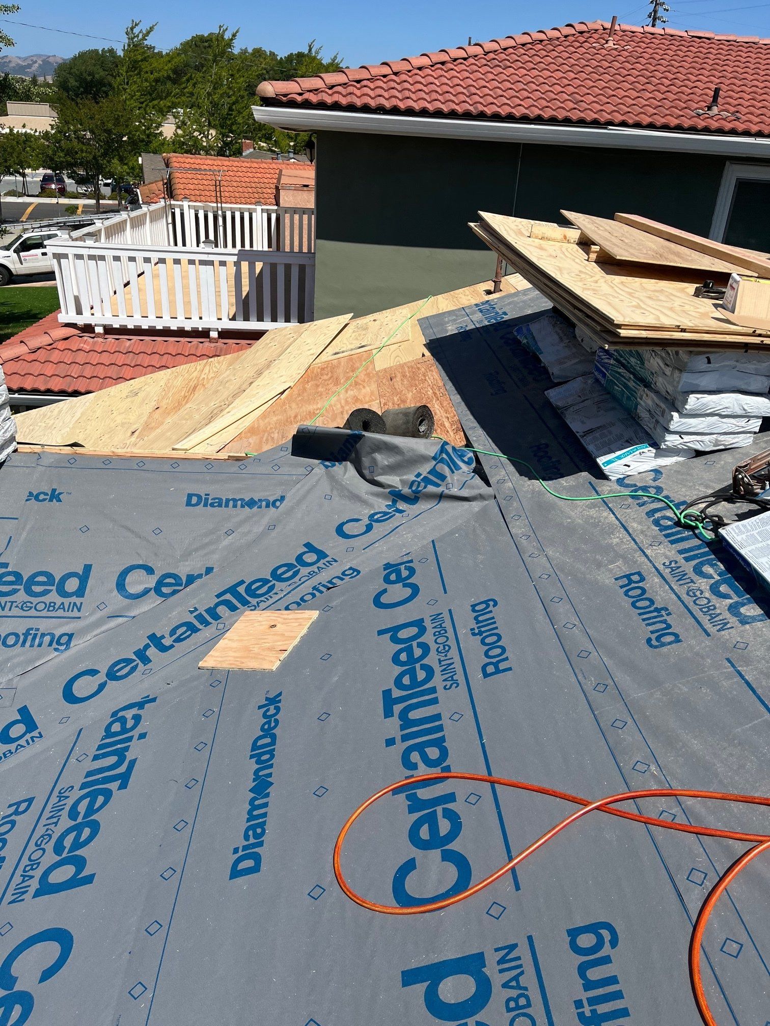 Roof being worked on: plywood, shingles, and underlayment visible, sunny day.