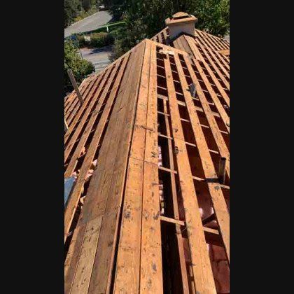 Wooden roof structure with exposed beams, undergoing repair or construction.