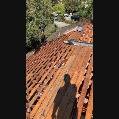 View of a partially dismantled roof, with exposed wooden beams. 