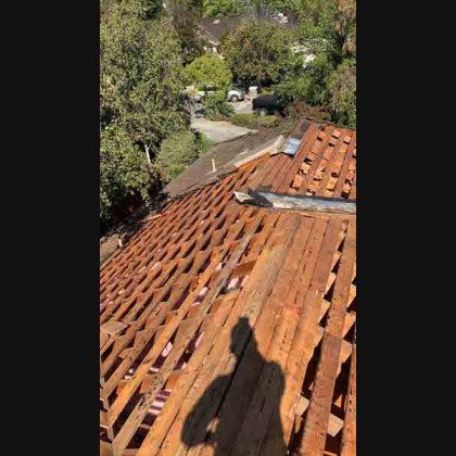 A roof under construction, exposed wood beams, bright sunlight, shadow of a person.