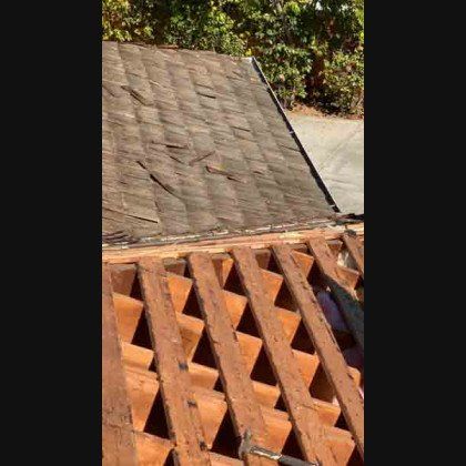 Damaged rooftop with wooden support beams in an outdoor setting.