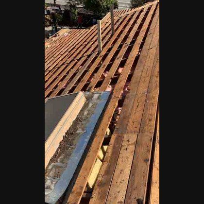 Wooden roof frame with some insulation visible; skylight and vent pipe.