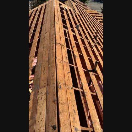 Wooden roof under construction; exposed beams and sheathing.