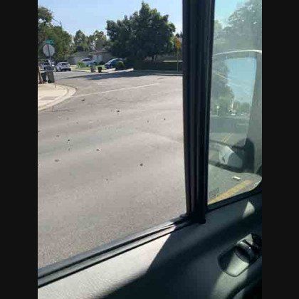 View from a vehicle window of an asphalt road and residential street corner.