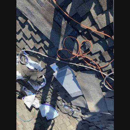 Overhead view of a roof with shingles, an orange cord, and some white debris.