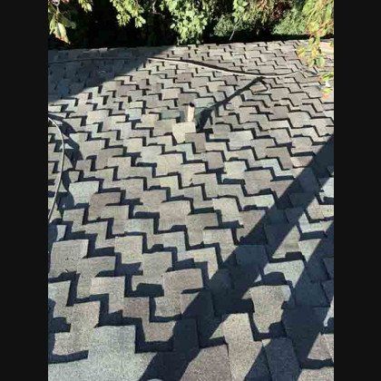 Asphalt shingle roof with shadows and a small vent pipe.