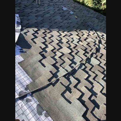 New asphalt shingles being installed on a roof, creating a zig-zag pattern, in daylight.