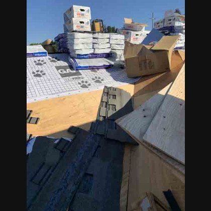 Rooftop with roofing supplies and new underlayment, ready for shingle installation on a sunny day.