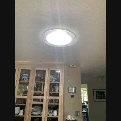 Skylight in a kitchen ceiling, above glass-door cabinets filled with dishes and glassware.