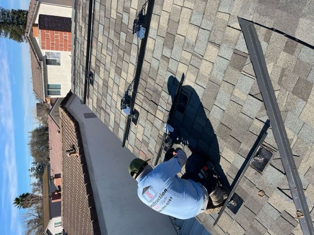 A person on a roof installing solar panels on a sunny day.