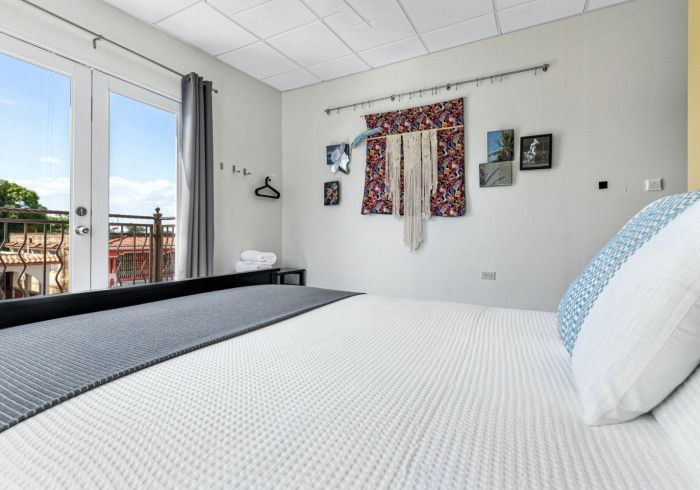 Bedroom with bed, French doors to a balcony, and colorful wall hangings.
