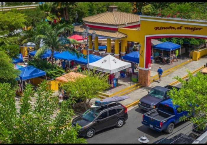 Outdoor market with tents, cars, and a sign in Spanish.