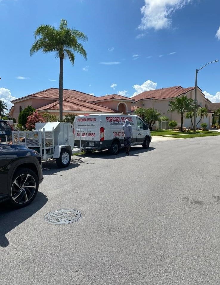 Street with parked utility trucks and a palm tree in front of tan homes under a blue sky