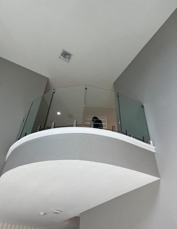 Curved white mezzanine with glass railing in a gray interior