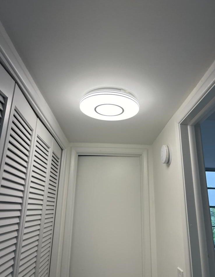 Narrow white hallway with louvered closet doors and a bright ceiling light