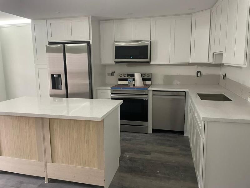 Modern kitchen with white cabinets, stainless steel appliances, and a large island with wood paneling