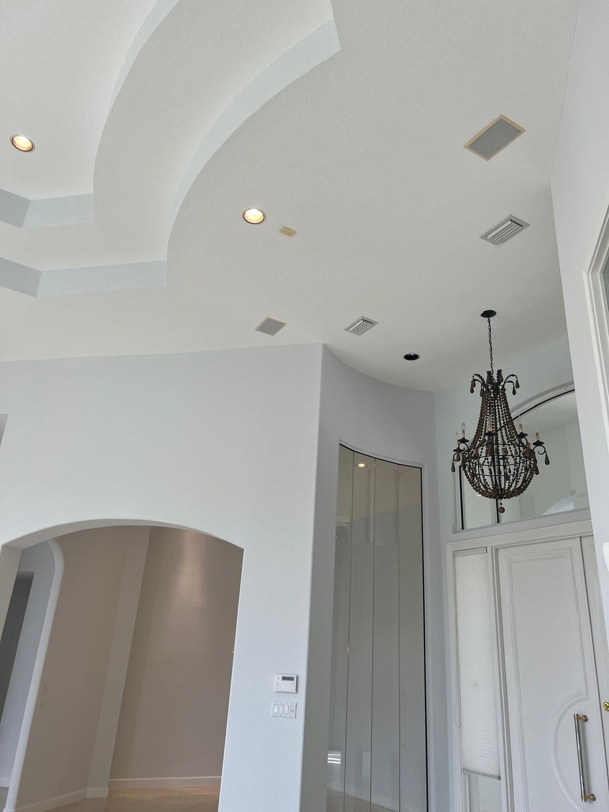 White entry hall with arched ceiling, recessed lights, gray doors, and a hanging chandelier