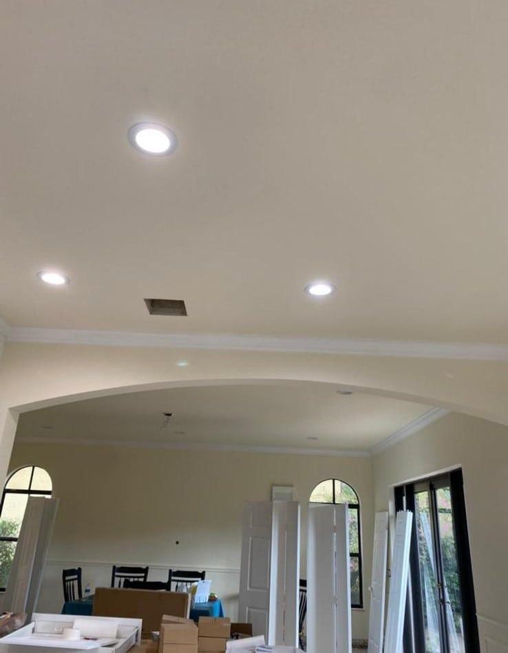 Living room with recessed lights, arched opening, and stacked white folding doors during renovation
