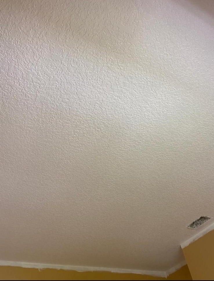 White textured ceiling with a small ceiling vent in the corner
