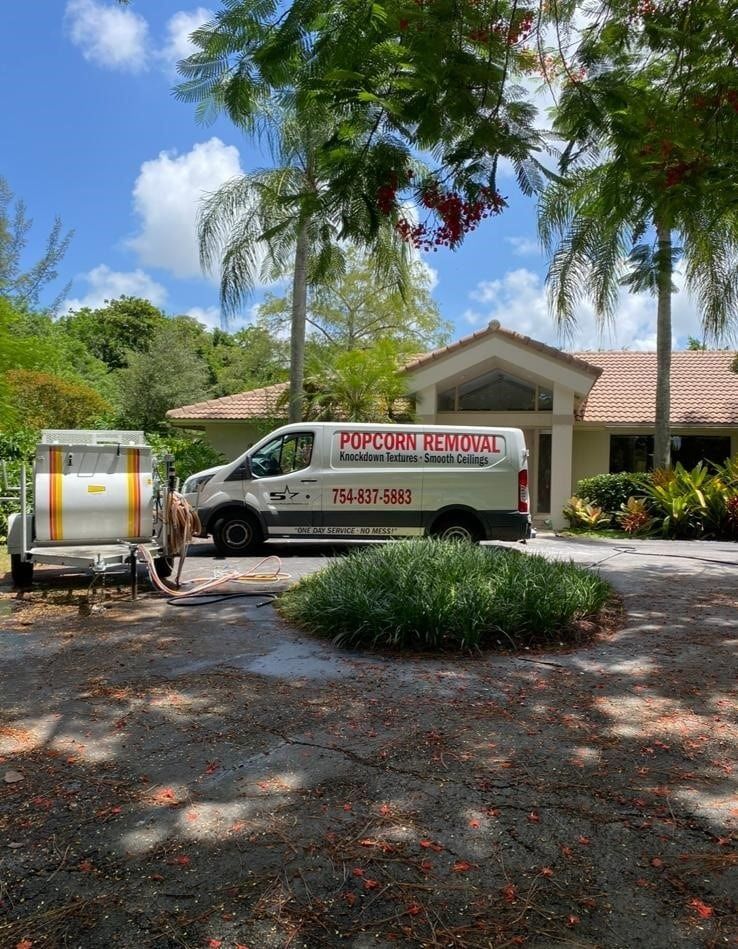 Pest control van parked beside a sprayer in a leafy driveway under palm trees
