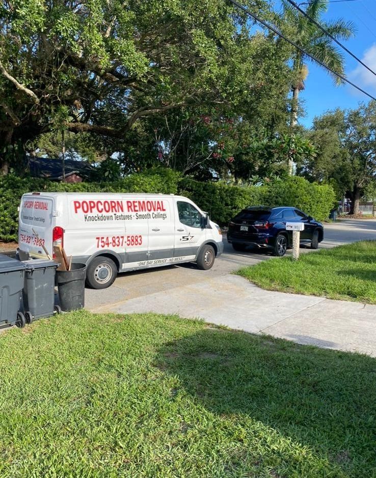 Popcorn Removal service van parked by a driveway beside a black SUV on a sunny residential street