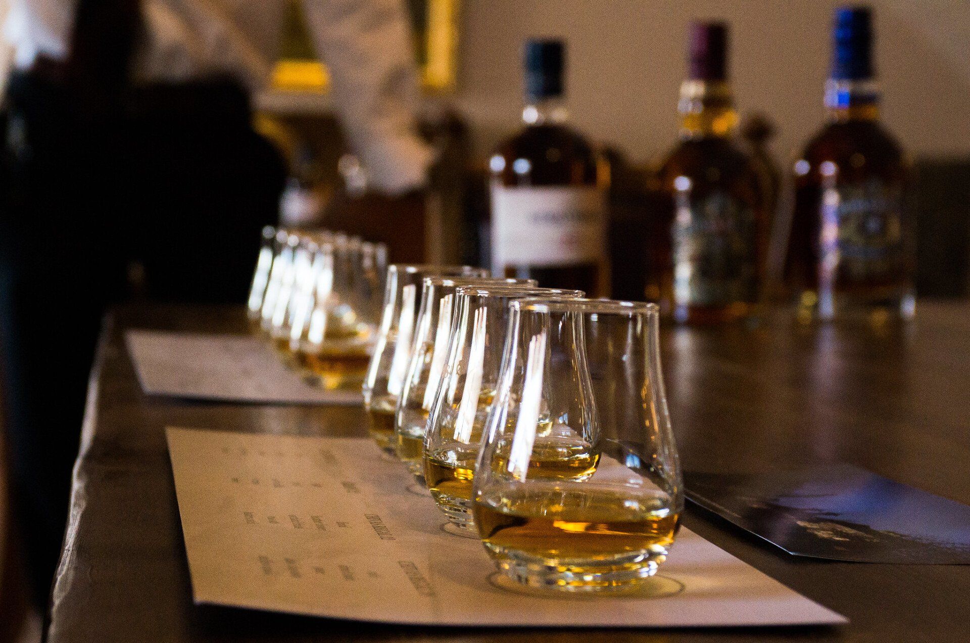 Several glasses of whiskey are lined up on a table