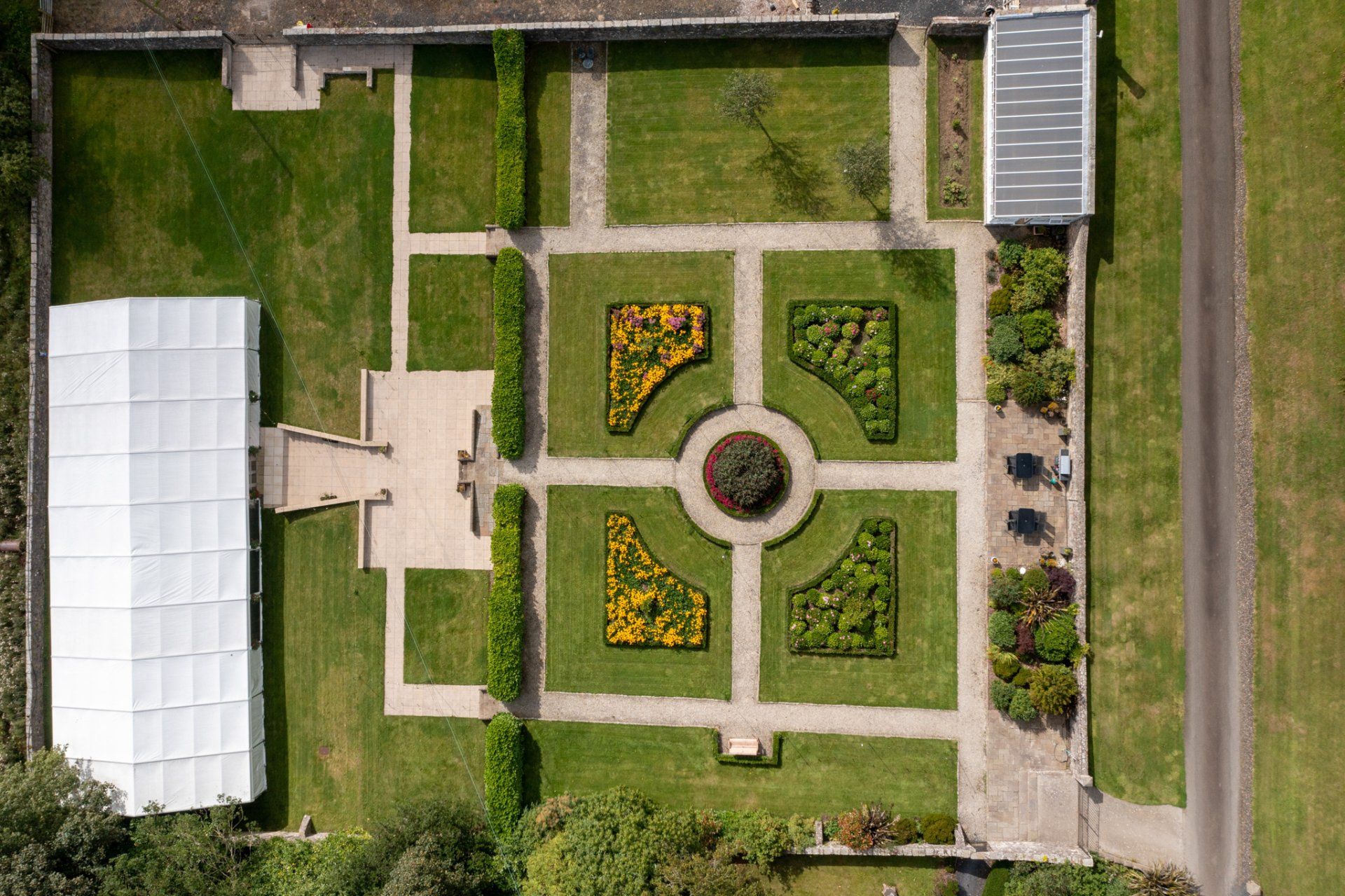 An aerial view of a garden with a white tent in the background