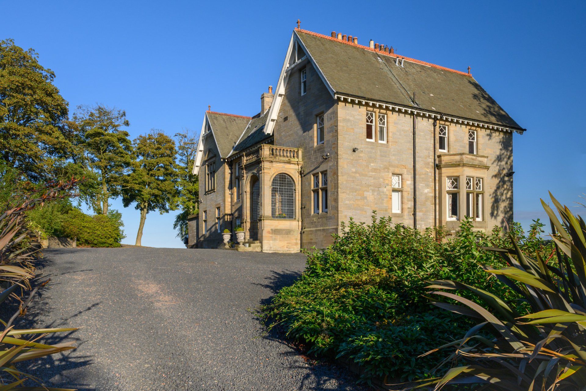 A large house with a gravel driveway leading up to it