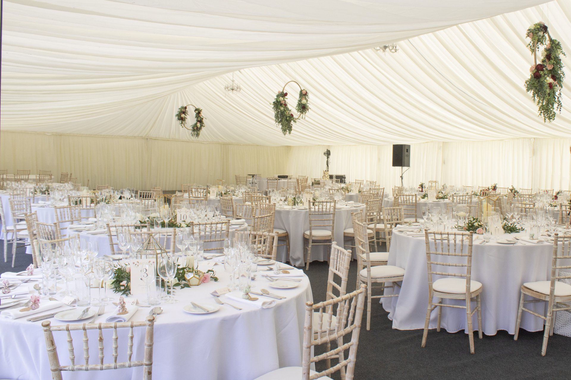 A large white tent with tables and chairs set up for a wedding reception